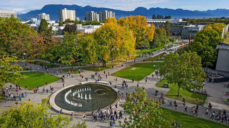 Aerial photo of the UBC campus showing the Martha Piper fountain, and mountains in the skyline.